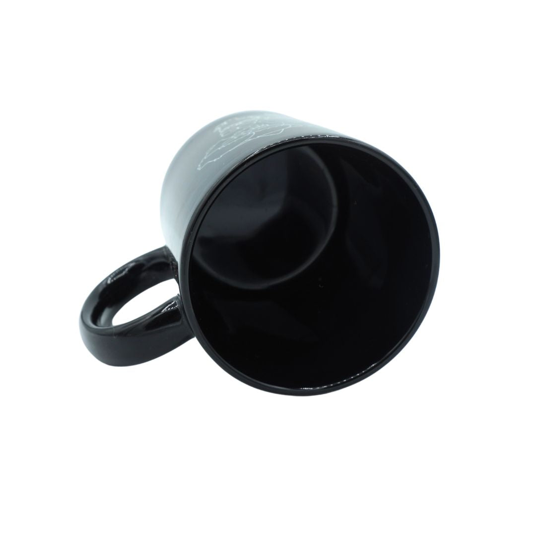 A glossy black ceramic mug with a matching black handle, shown from an angled top-down perspective on a plain white background.