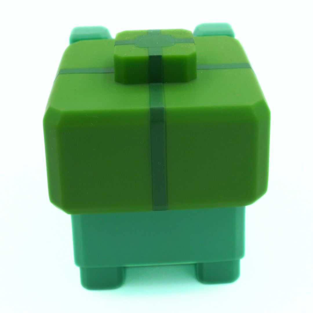 Green cube-shaped toy with a bow on a white background