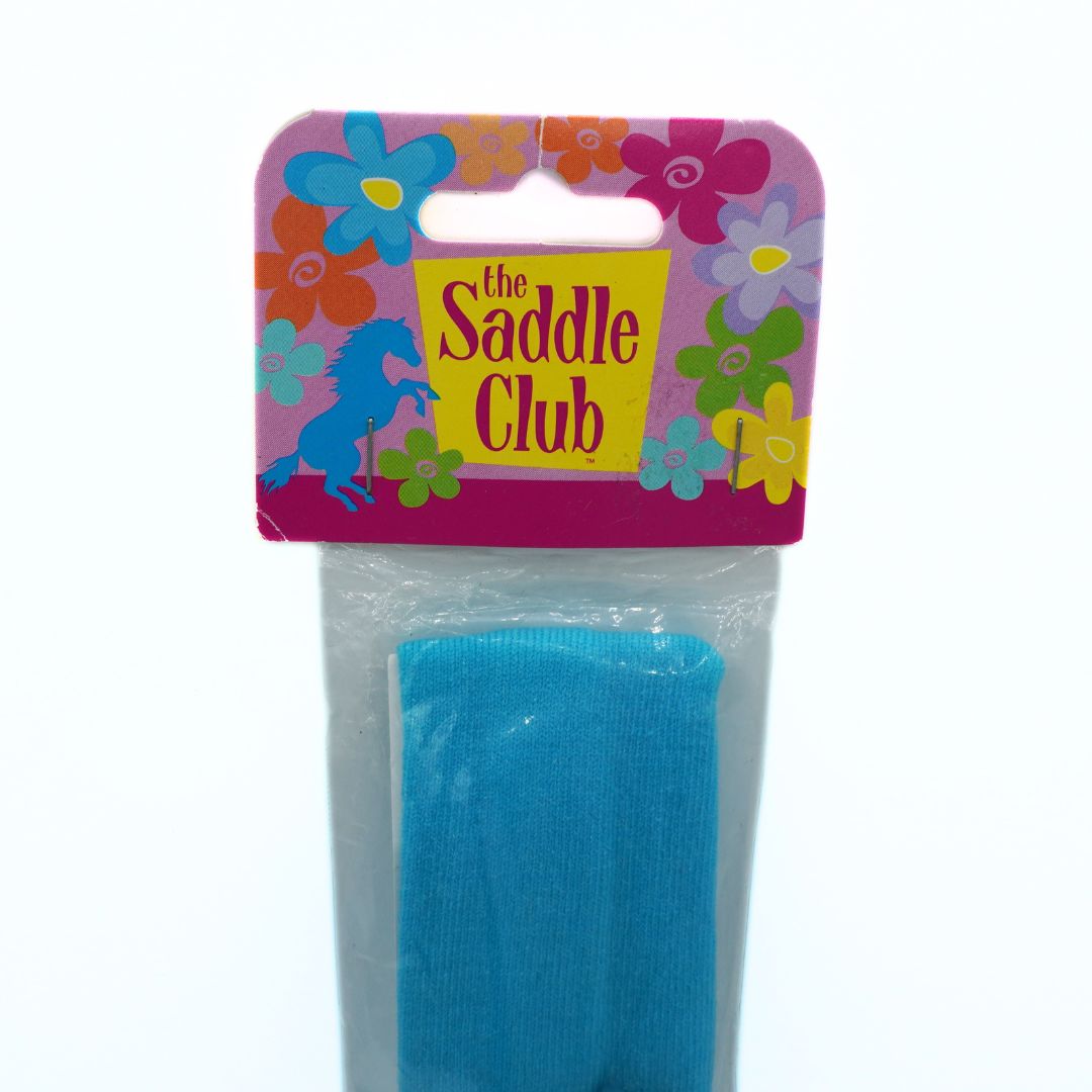 Blue headband in packaging with 'The Saddle Club' branding on a white background