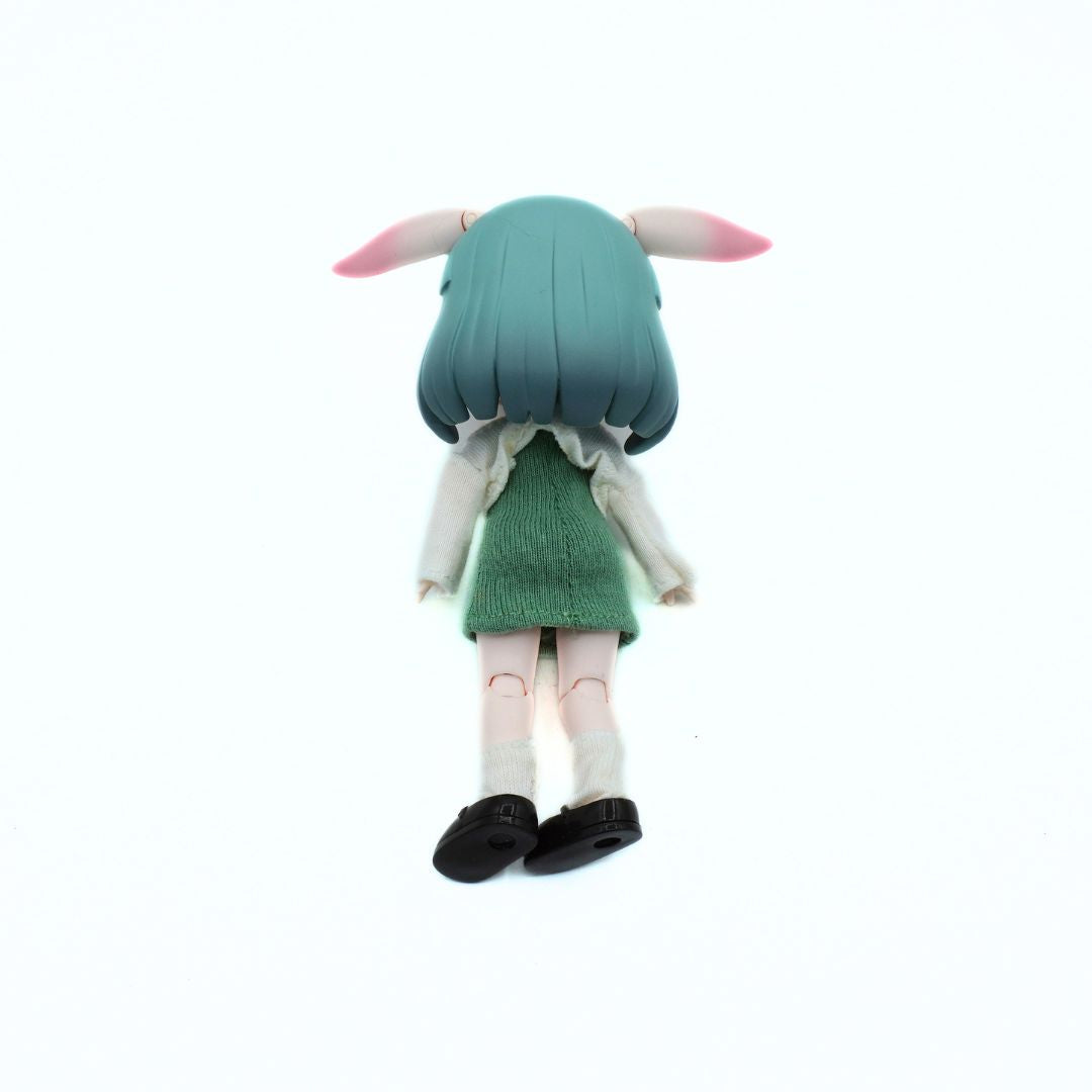 A small anime-style doll or figurine shown from the back on a plain white background. The figure has mint green hair with pink tips, a green dress, a white cardigan, white socks, and black shoes.