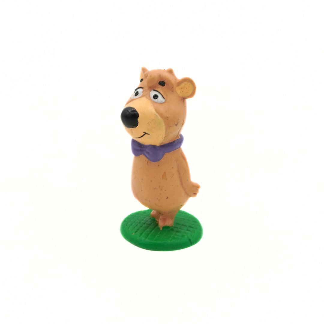 Cartoon bear figurine with a purple scarf on a white background