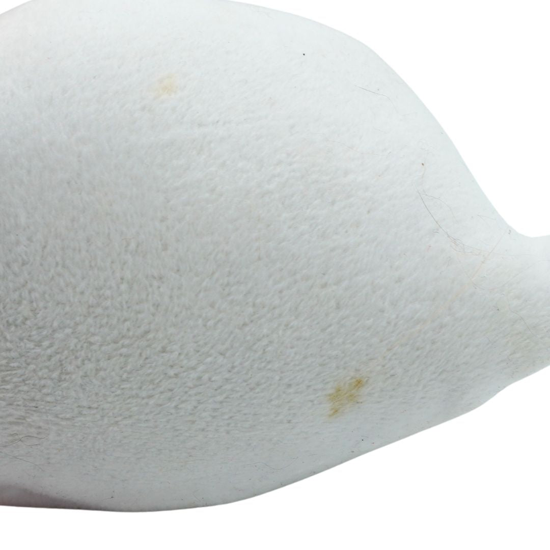 A close-up of a white textured fabric or faux fur surface against a white background, showing a few small yellowish stains.