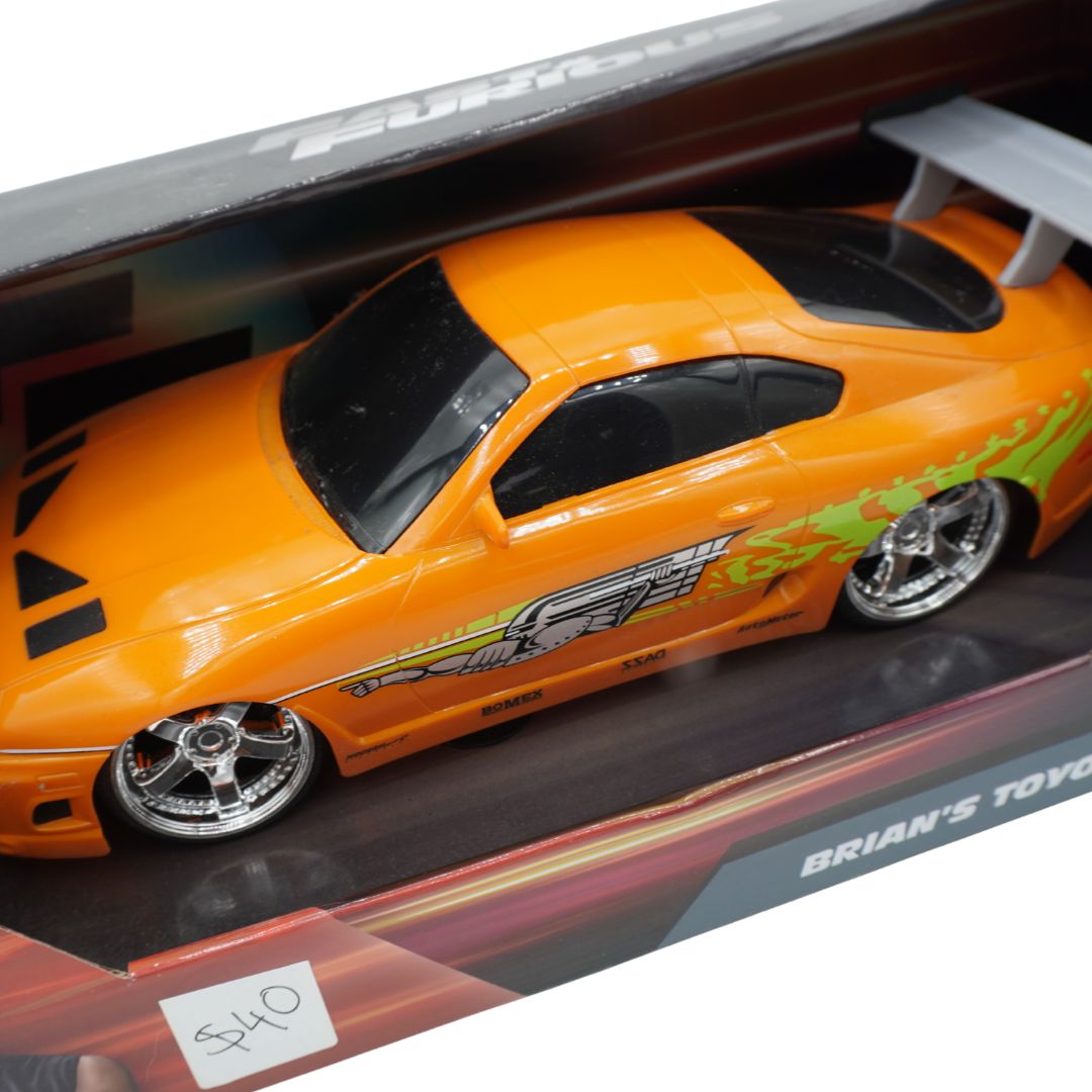 An orange model sports car with green and white flame decals, displayed inside its retail packaging box.