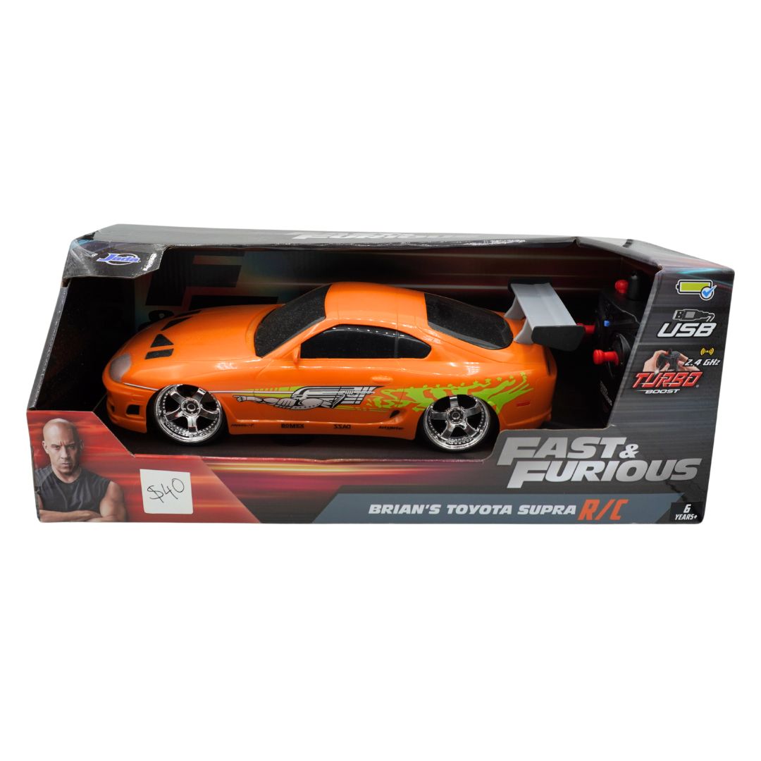 An orange RC Toyota Supra toy car in its original retail packaging, featuring a graphic of Jason Statham from Fast & Furious on the box and decals on the car itself.