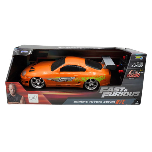 An orange RC Toyota Supra toy car in its original retail packaging, featuring a graphic of Jason Statham from Fast & Furious on the box and decals on the car itself.
