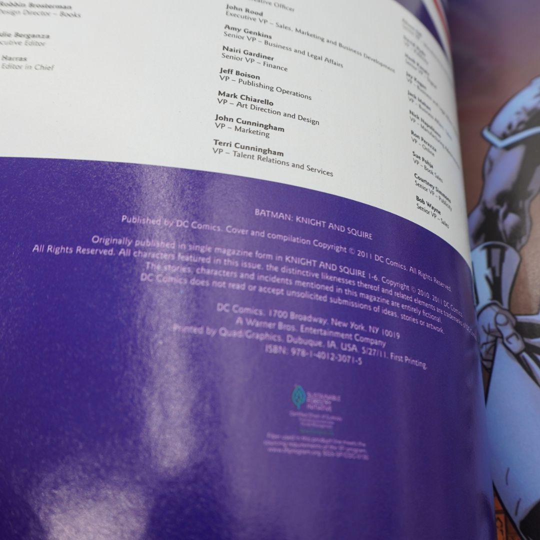 An open book or magazine page showing printed text and a large purple title block reading 'BATMAN: KNIGHT AND SQUIRE'. The left page has white text at the top and a purple block with publisher information at the bottom.