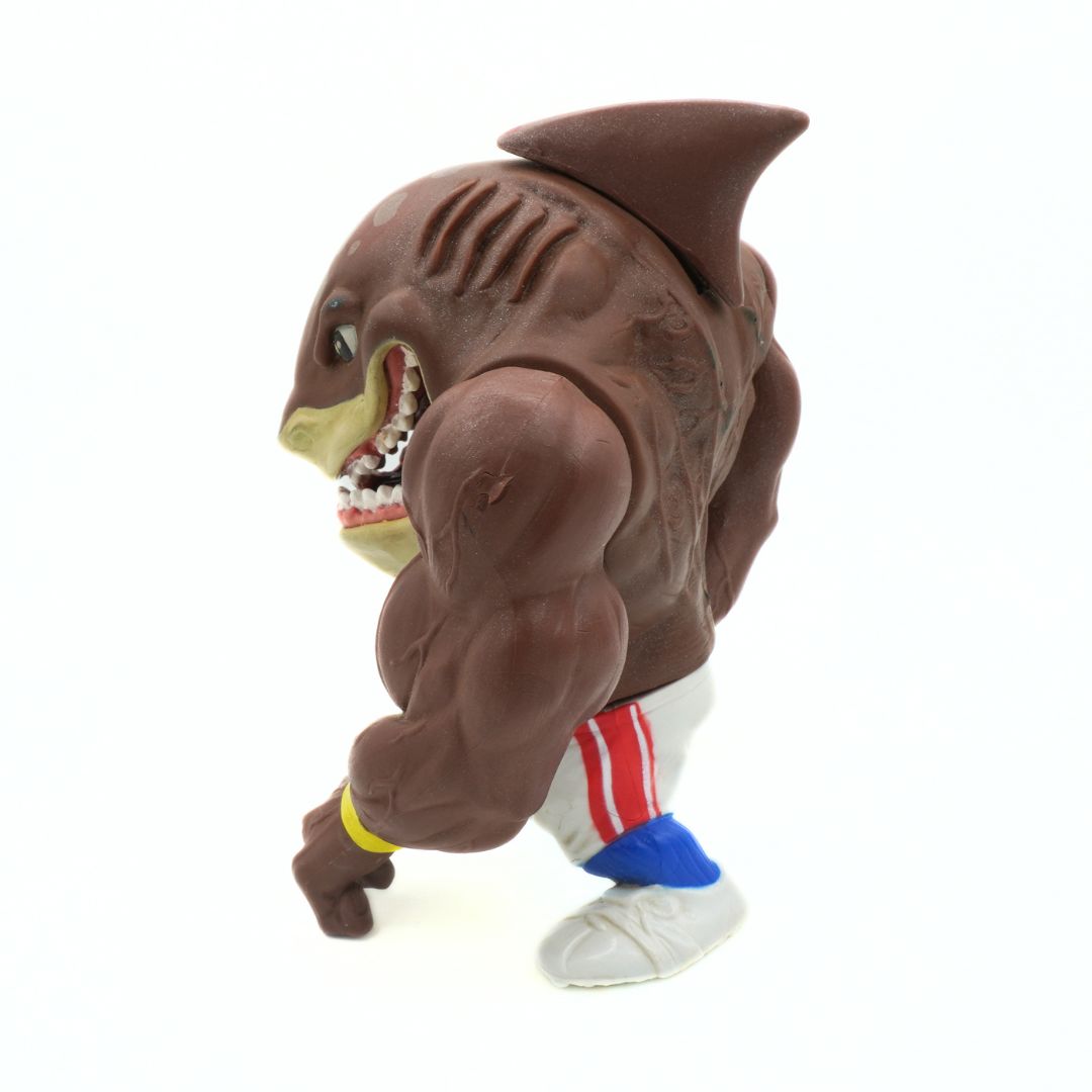 Toy figure of a muscular shark with a human-like body on a white background