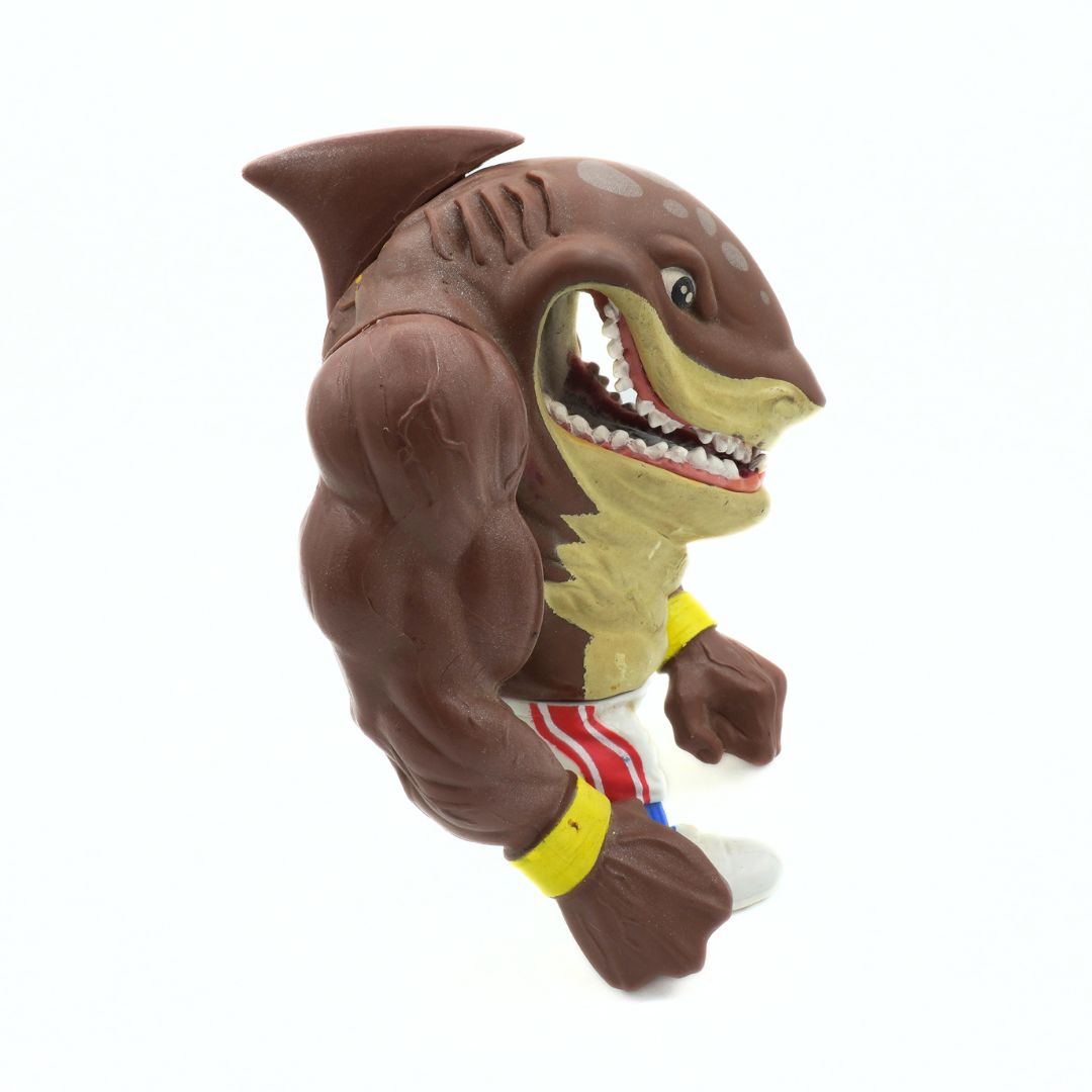 Toy figure of a shark with a muscular build on a white background
