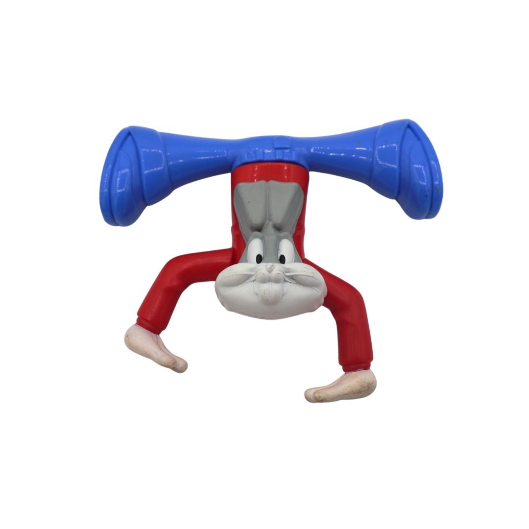 A plastic toy figure of Bugs Bunny posed upside down, holding a blue horn-shaped object above his head, on a plain white background.