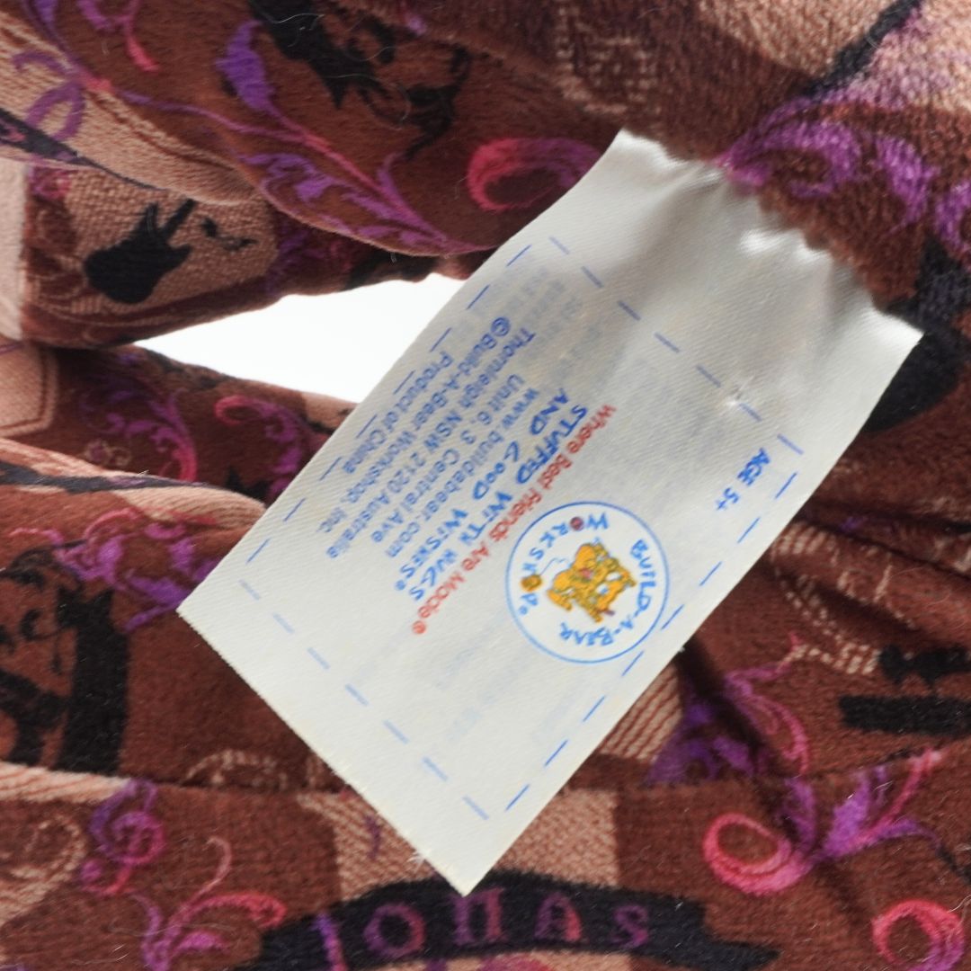 Close-up of a tag on a brown fabric with colorful patterns, featuring a logo and text.