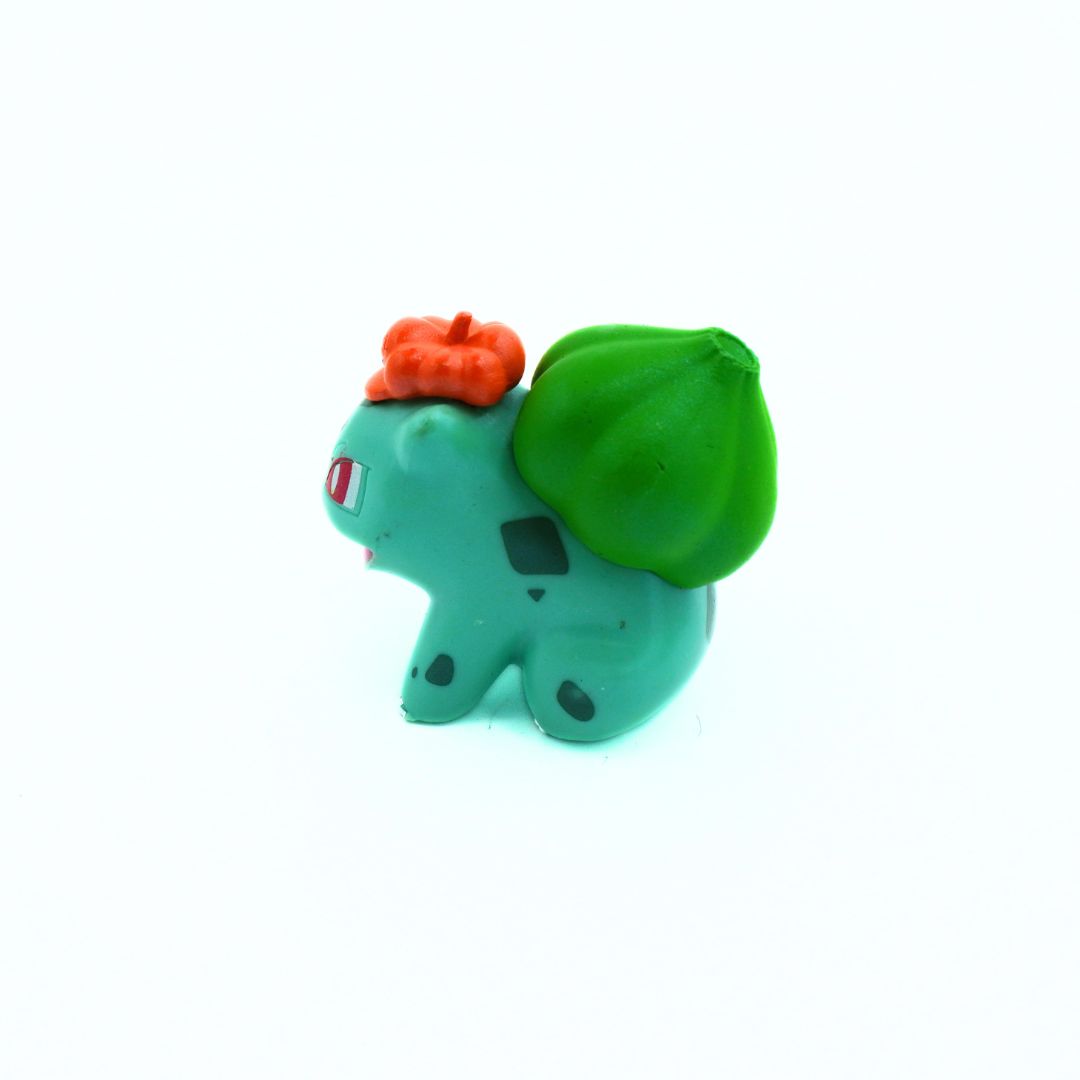 Small green dinosaur toy with orange hair on a white background