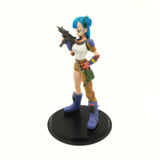 A collectible anime figurine of a female character with bright blue hair, wearing a white tank top, brown pants, and blue boots, holding a black submachine gun while standing on a round black display base against a plain white background.