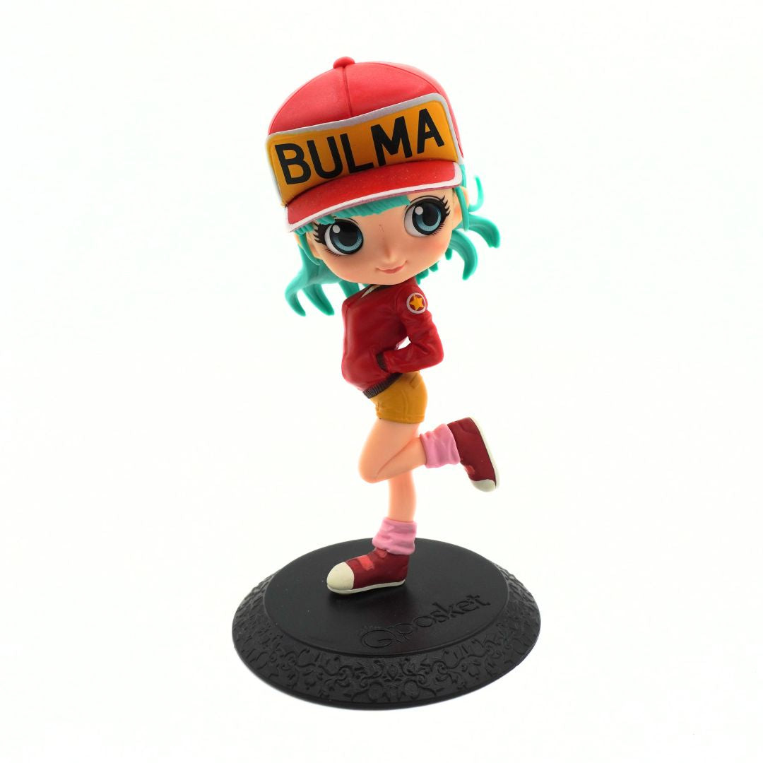 A stylized collectible figurine of the anime character Bulma, wearing a red cap with 'BULMA' written on it, a red jacket, yellow shorts, pink socks, and red sneakers, standing on a black textured base.