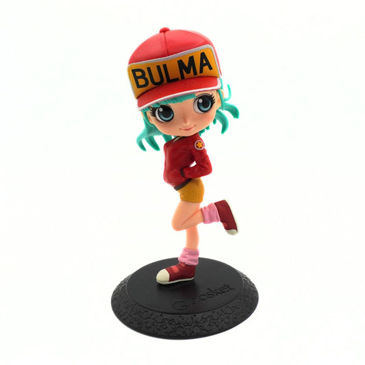 A stylized collectible figurine of the anime character Bulma, wearing a red cap with 'BULMA' written on it, a red jacket, yellow shorts, pink socks, and red sneakers, standing on a black textured base.