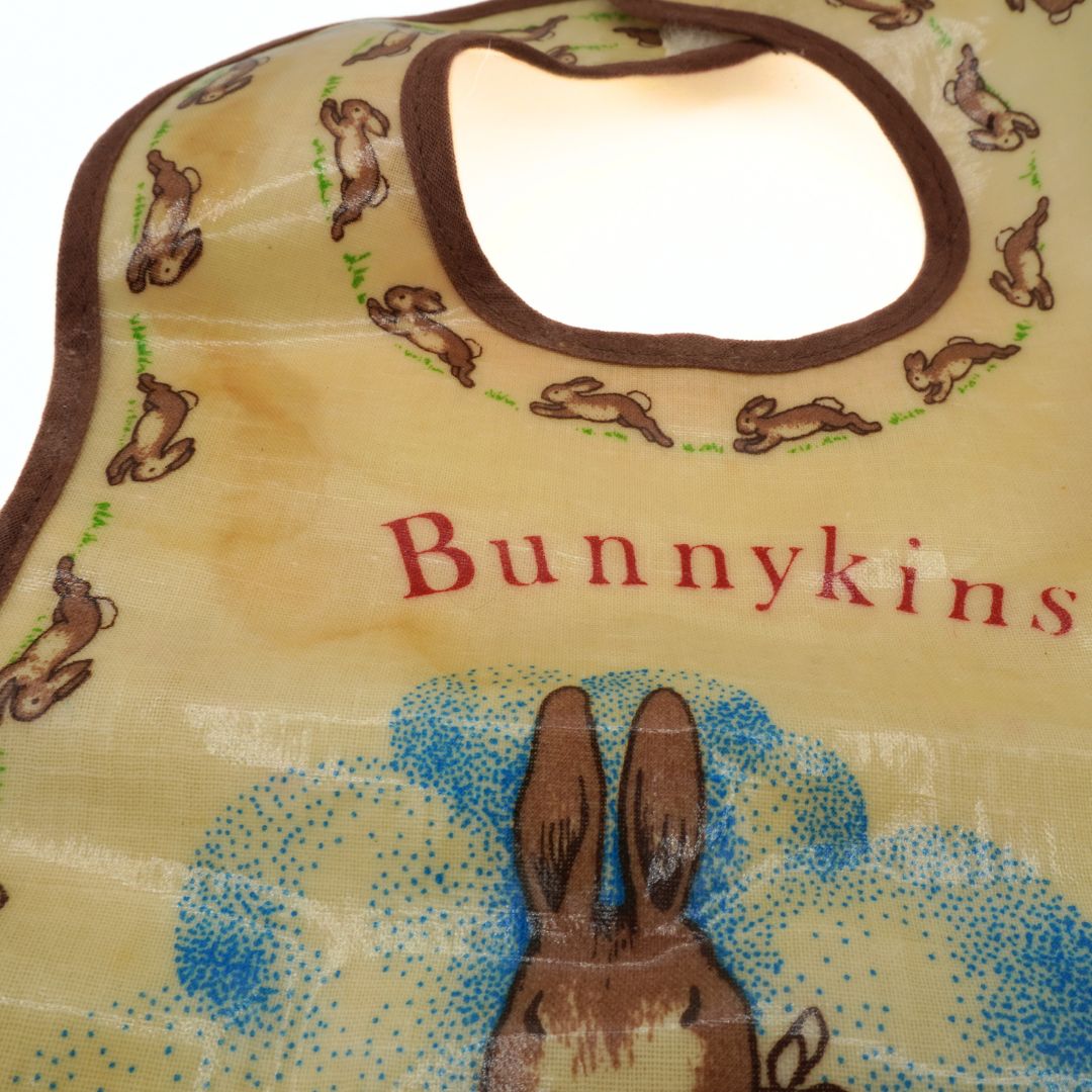 Baby bib with rabbit illustrations and 'Bunnykins' text on a beige background
