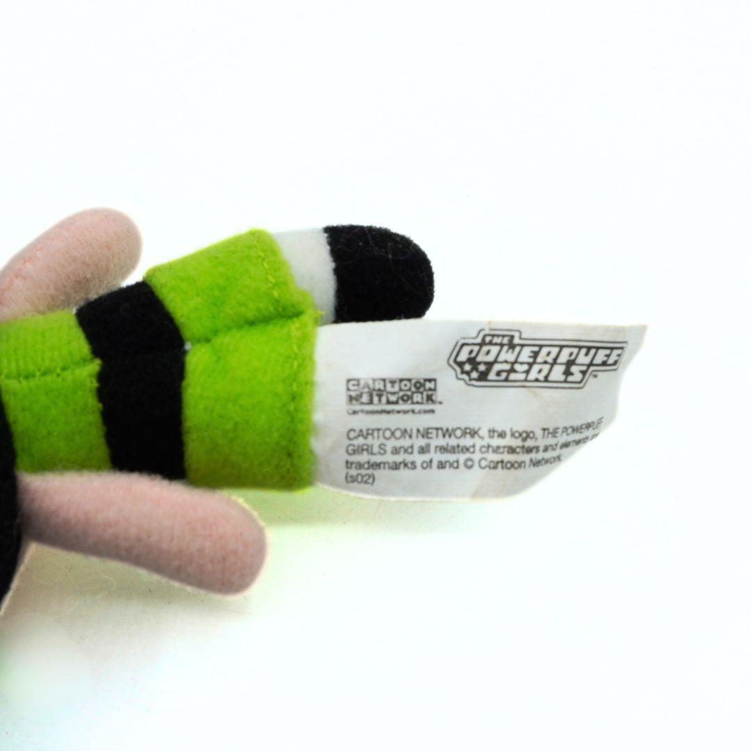 Green and black plush toy with a label on a white background