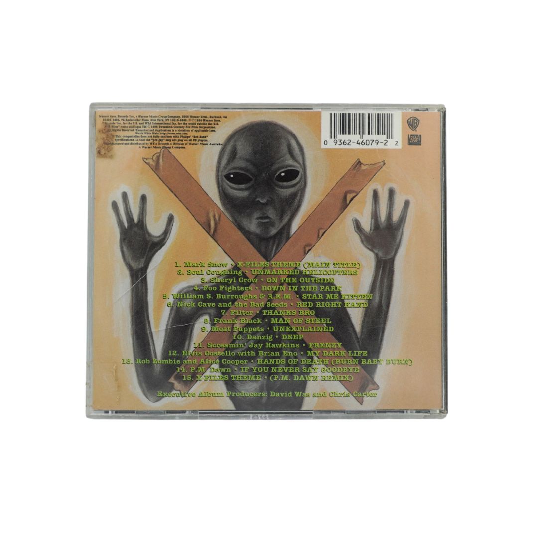 The back cover of a CD case featuring a black alien with outstretched hands against a beige background with a brown X.