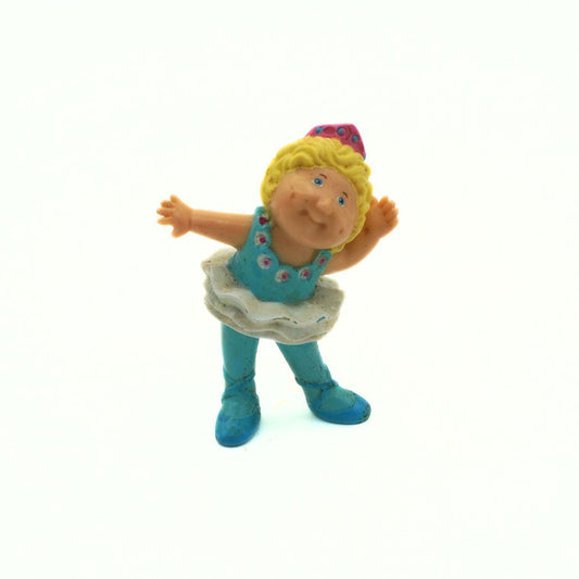Toy figure of a character with blonde hair, blue dress, and boots on a white background