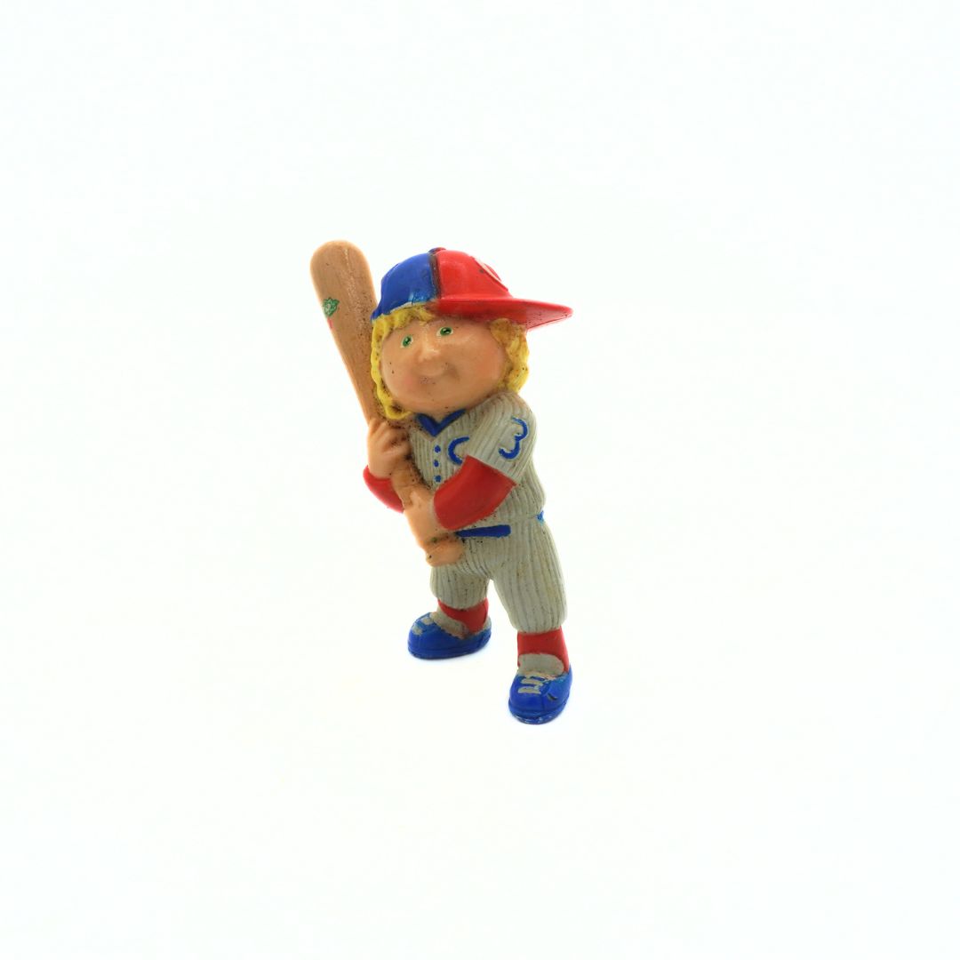 Figurine of a baseball player in a blue and red uniform holding a bat on a white background