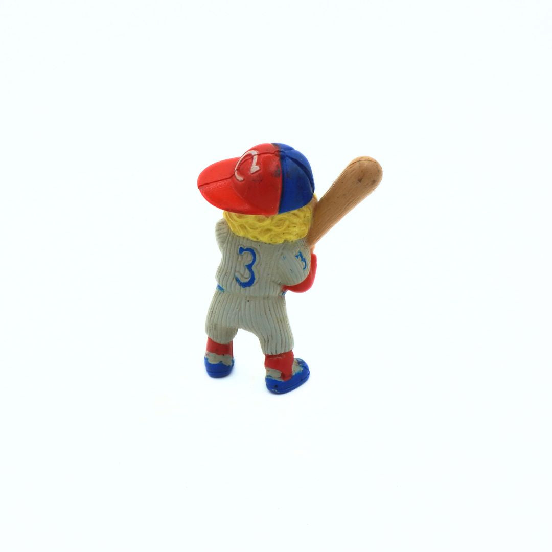 Toy figure of a baseball player with a red and blue cap, yellow jersey, and gray pants on a white background.