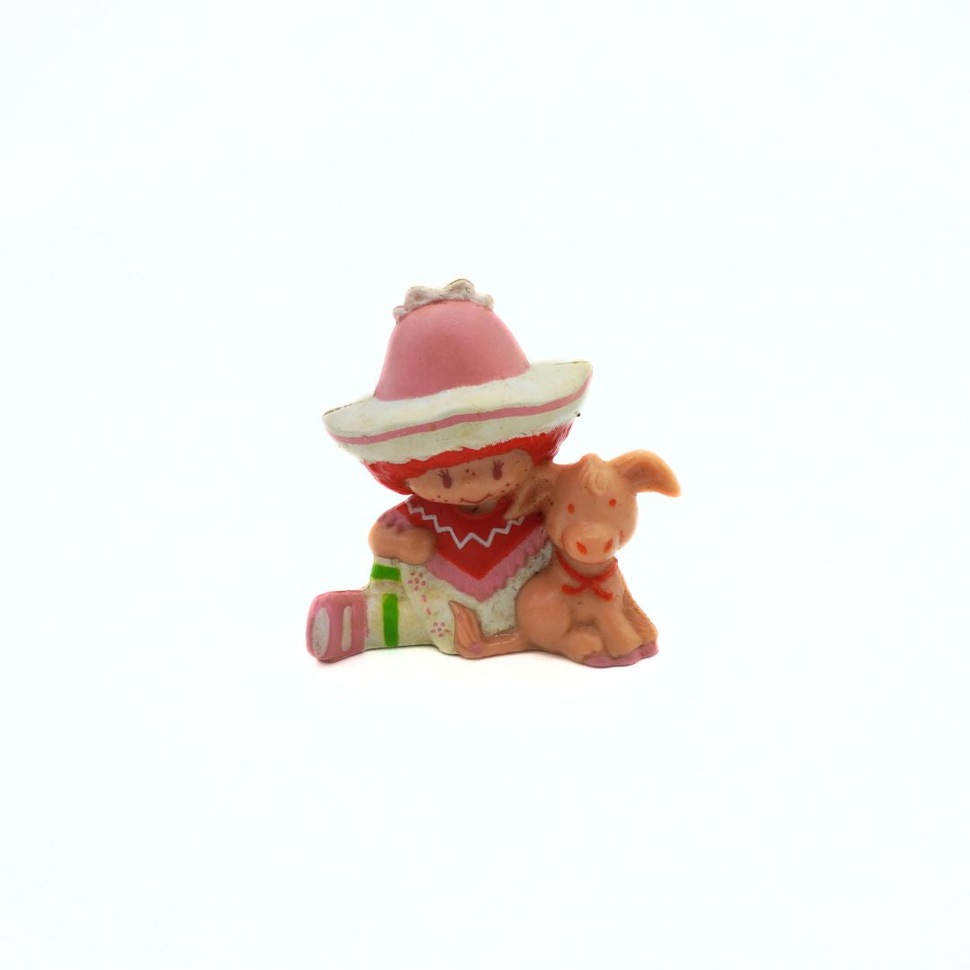 Small figurine of a child in a pink hat with a dog on a white background