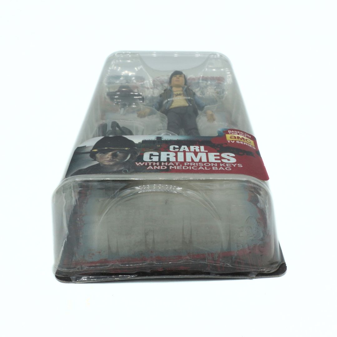 Action figure of Carl Grimes from 'The Walking Dead' in packaging on a white background