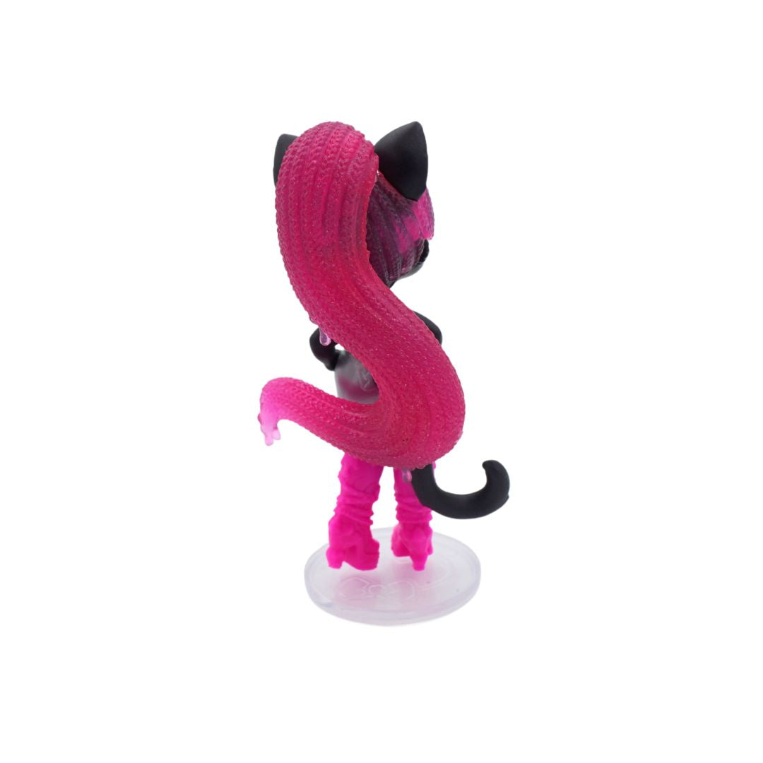 Small Catty Noir doll with pink hair and a black pamphlet on a white background