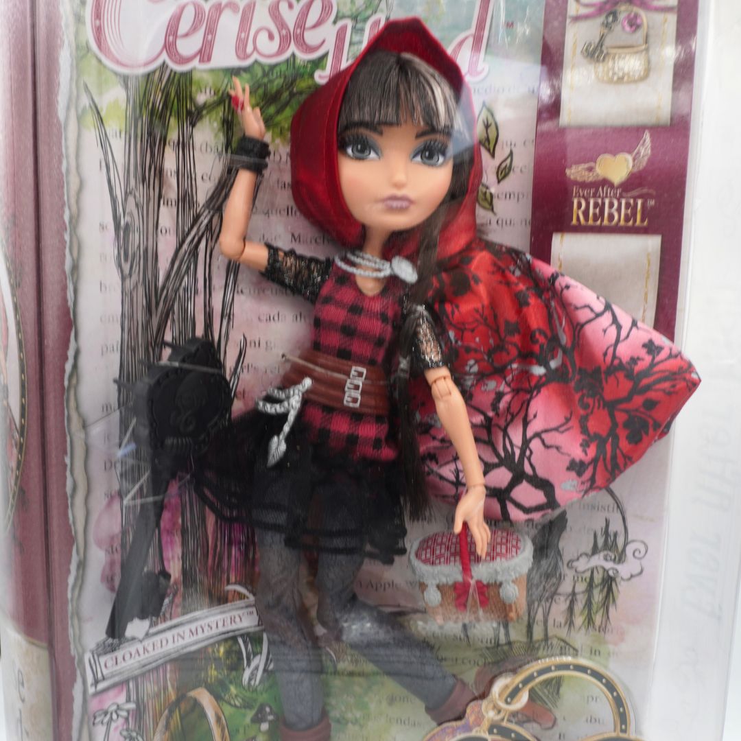 Doll in a red hooded outfit with a colorful box in the background