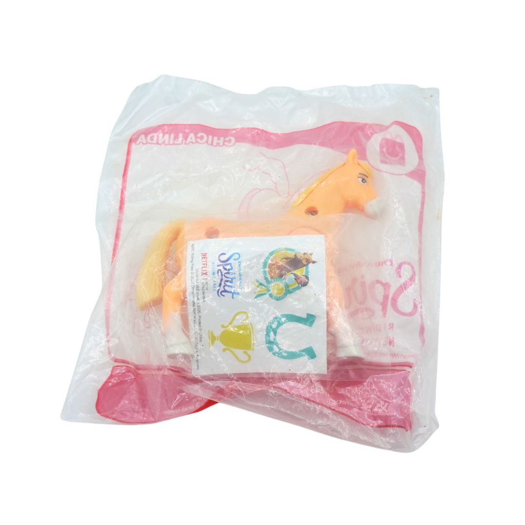 A packaged toy horse from the movie 'Spirit' sealed in a clear plastic bag with pink branding and a small character card.