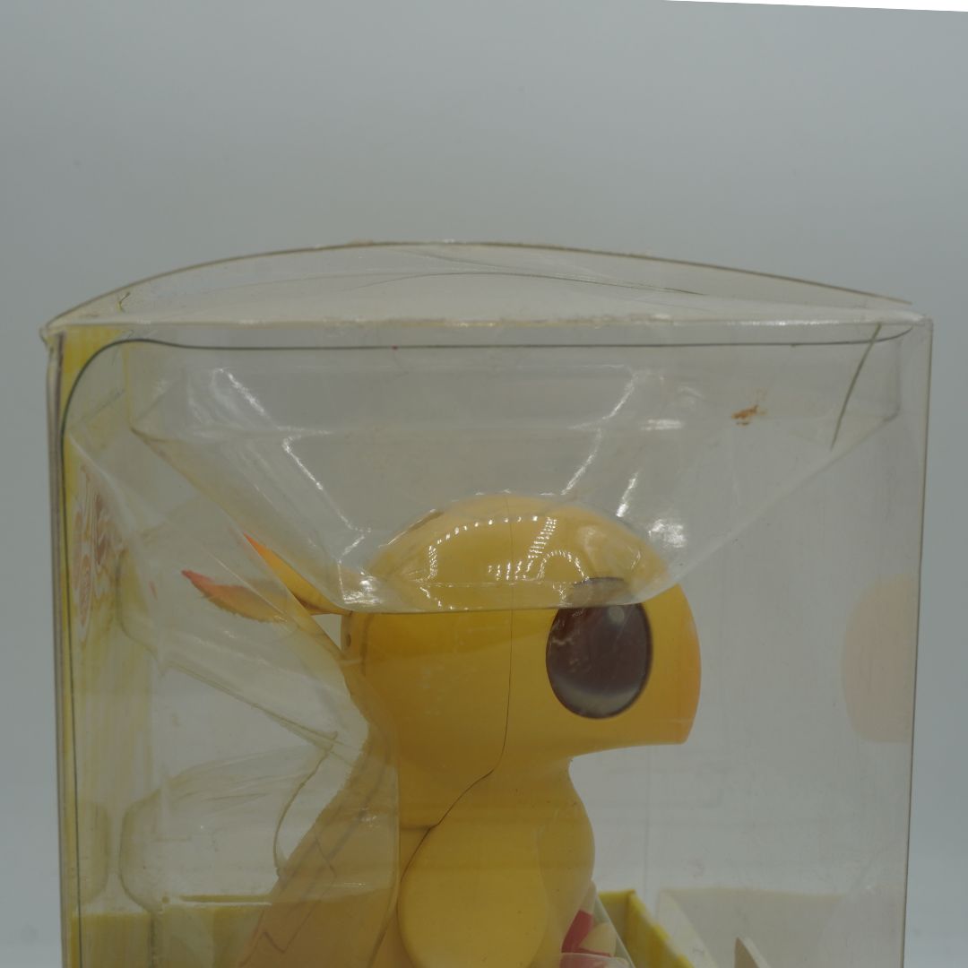 Yellow bird toy in a clear plastic packaging on a white background