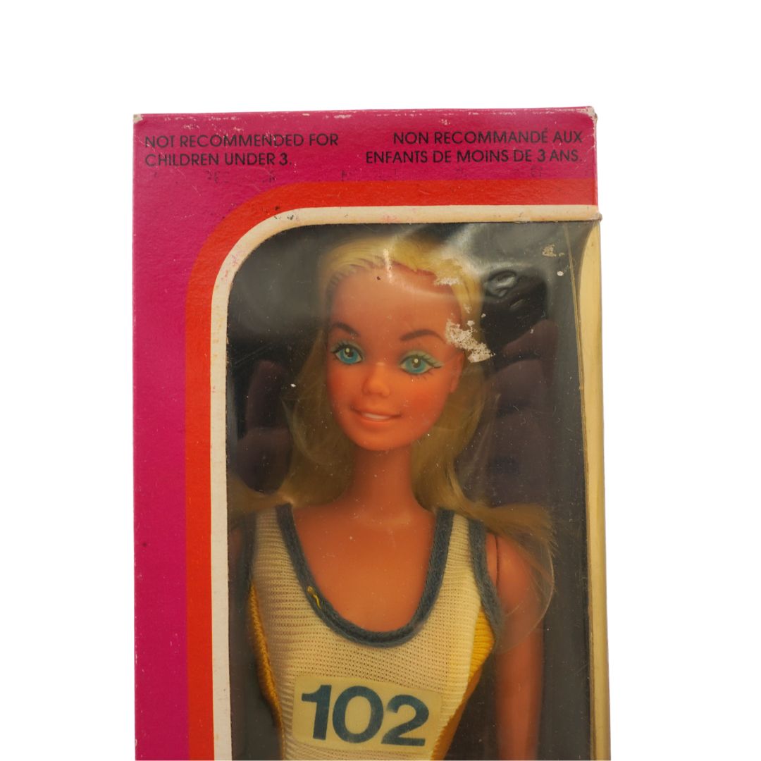 Barbie doll in packaging with a pink border and text