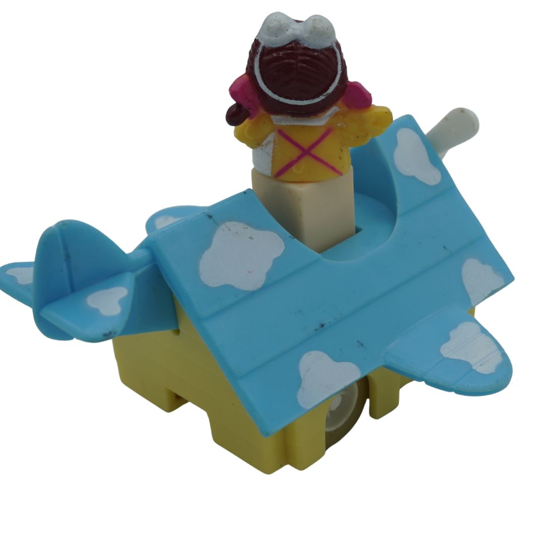 A vintage plastic toy airplane door opener with a clown figure popping out of the open door, set against a plain white background.
