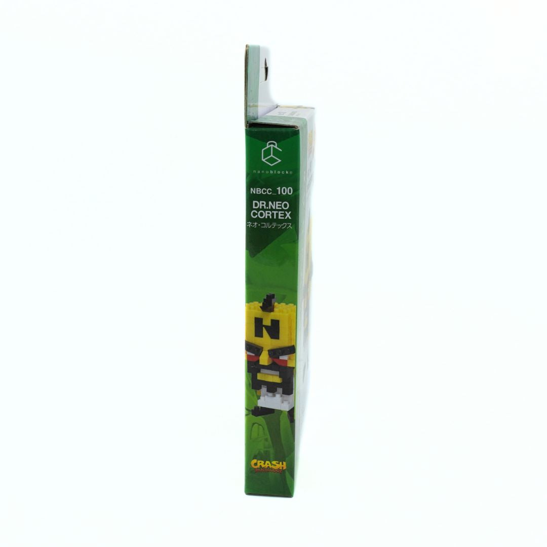 A tall, narrow retail package standing upright on a plain white background. The box is predominantly green with a yellow panel showing a stylized block-letter face and small product imagery near the bottom.