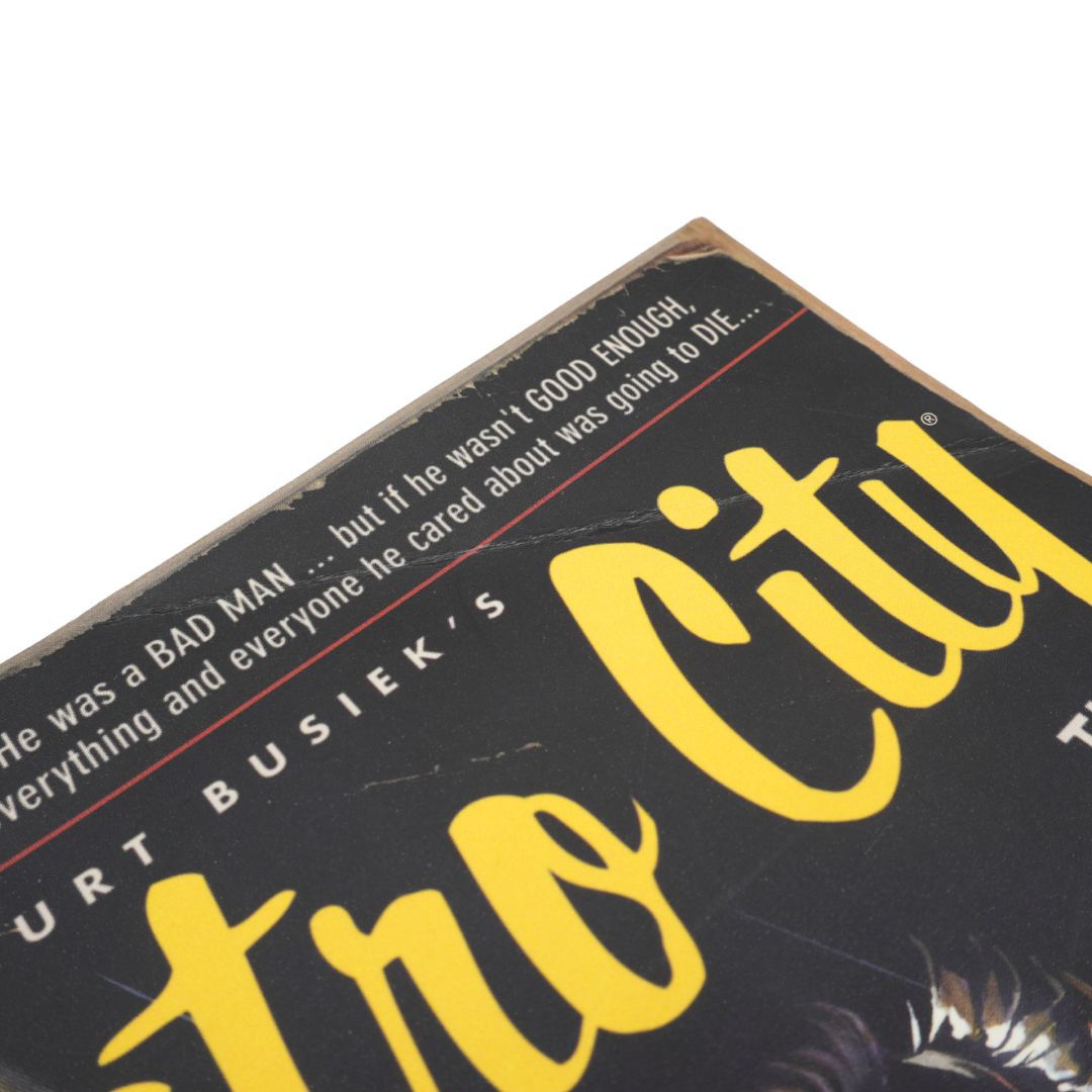 A close-up angled shot of a book cover featuring a black background with large yellow script title text and white review text at the top, photographed on a white background.