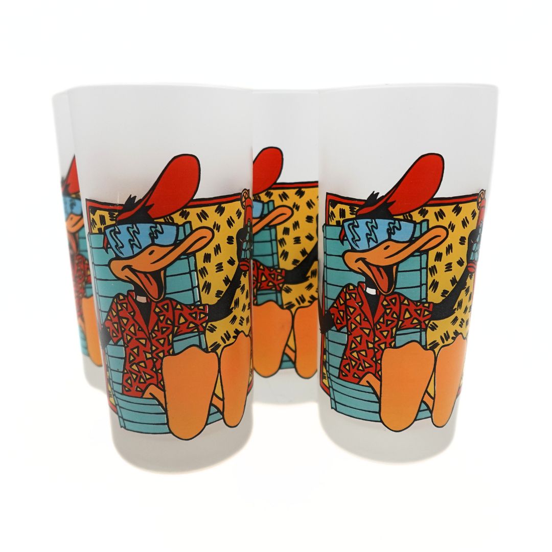 Photo of a set of four 1991 Daffy Duck glasses with a red, blue, orange and yellow 90s colour palette