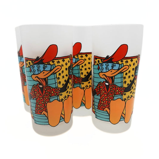 Photo of a set of four 1991 Daffy Duck glasses with a red, blue, orange and yellow 90s colour palette