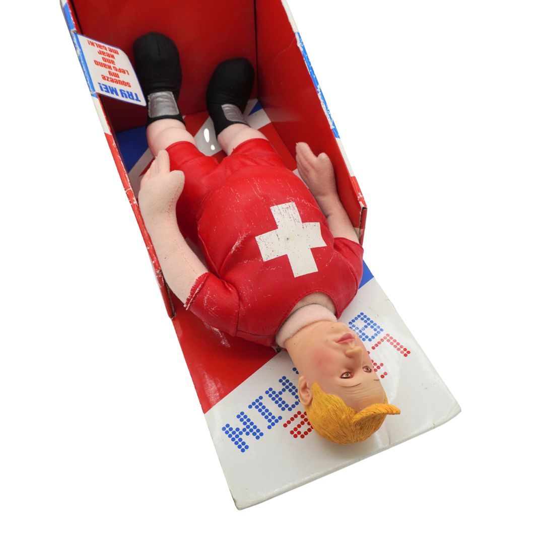A vintage toy inside its red and white original packaging box, photographed on a solid white background.