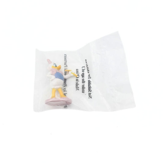 Photo of a Daisy Duck cake topper still in its original packaging, on a pinkish purple platform and holding a yellow flower