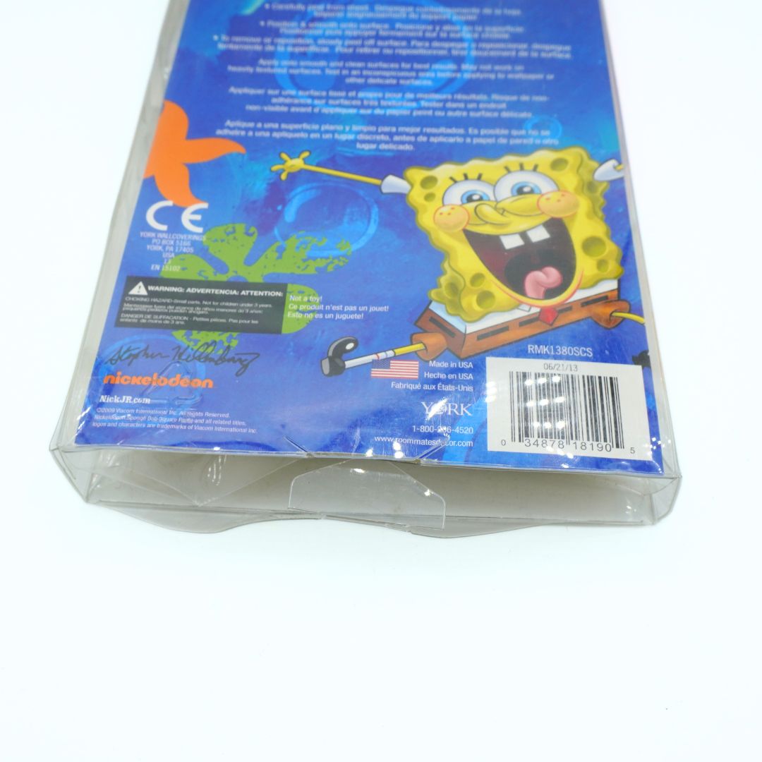 Back view of a SpongeBob SquarePants plastic shrink-wrapped case on a white background, showing character artwork, text, a barcode, and a signature.