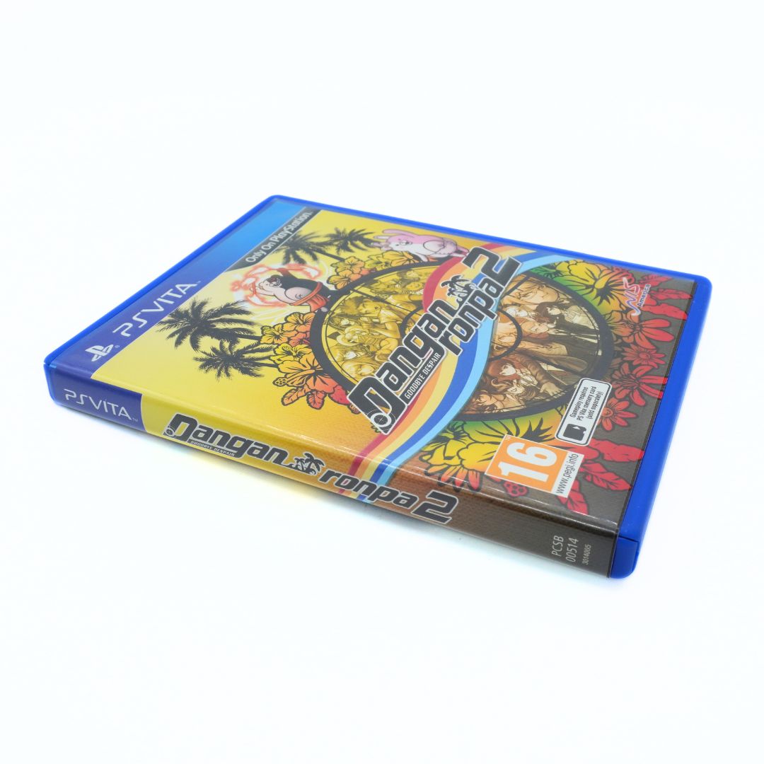 A PlayStation Vita game case for 'Dangan Ronpa 2' resting on a plain white background. The blue plastic case features a colorful tropical-themed cover with palm trees, a yellow-to-orange gradient sky, and a circular character portrait.