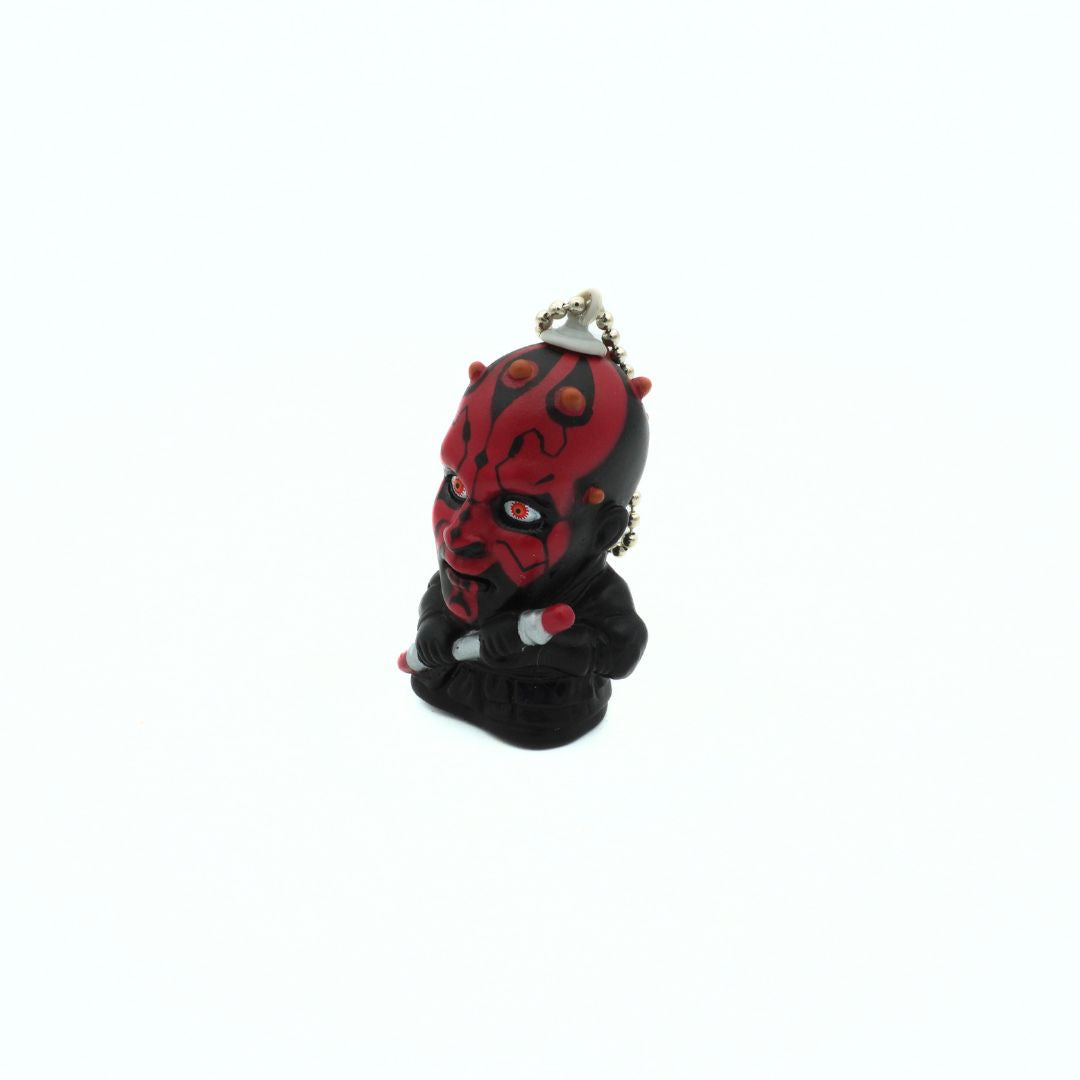 A vintage Star Wars Darth Maul keychain holding his dual ended lightsaber
