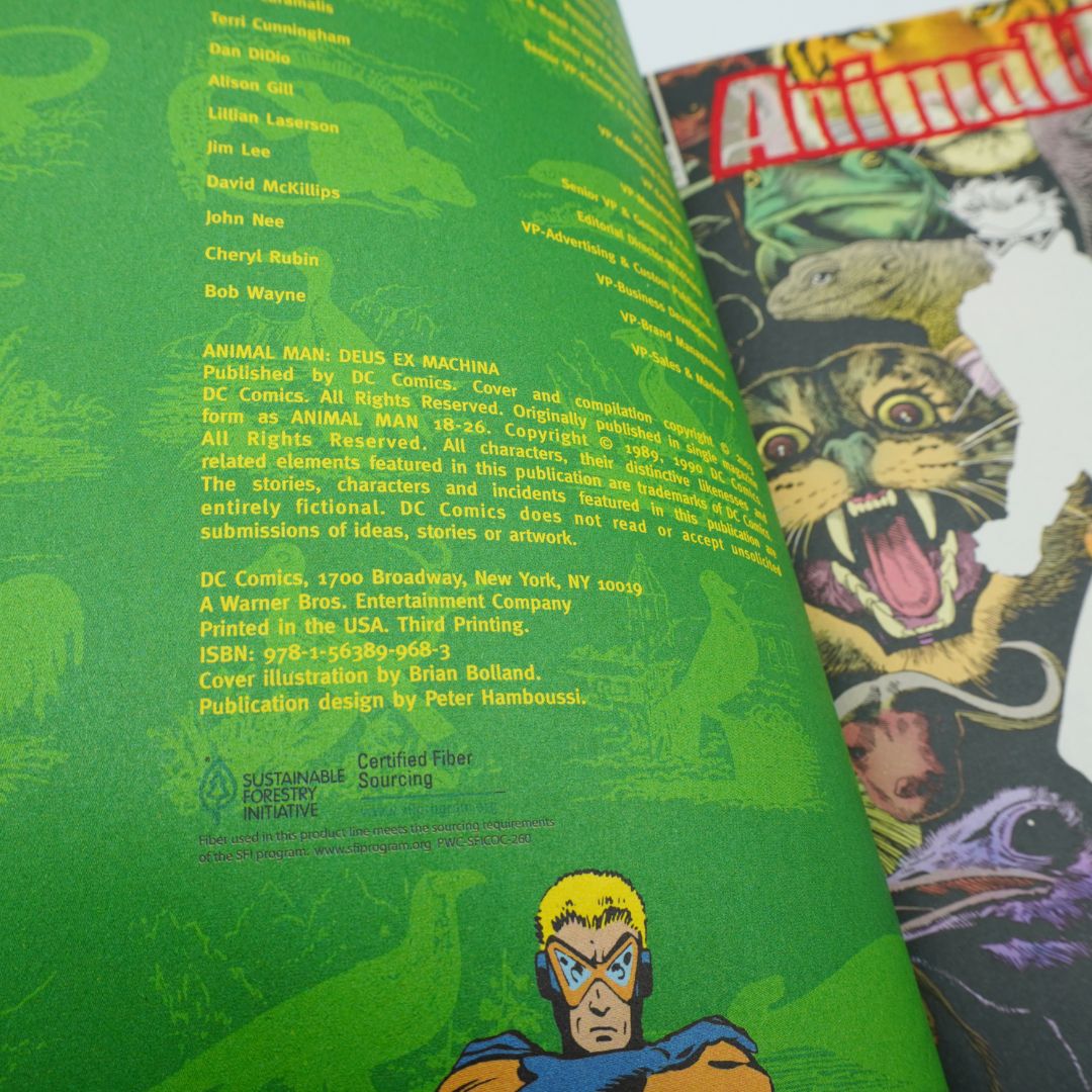An angled close-up of a comic book's interior printed pages, showing green cover text and credits alongside a colorful cover illustration with the title 'Animal Man' visible at the top.