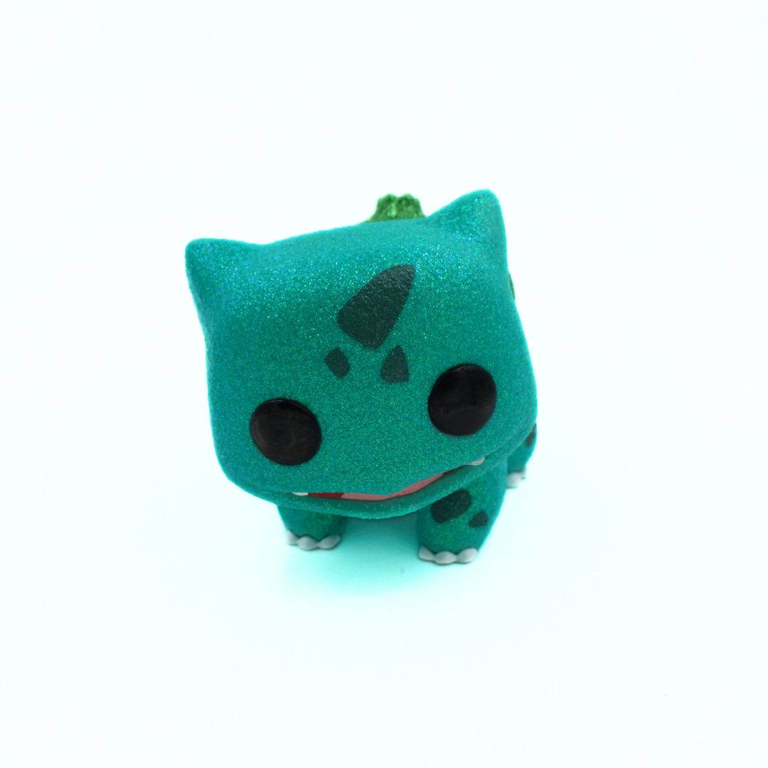 Small green plush toy with black spots on a white background