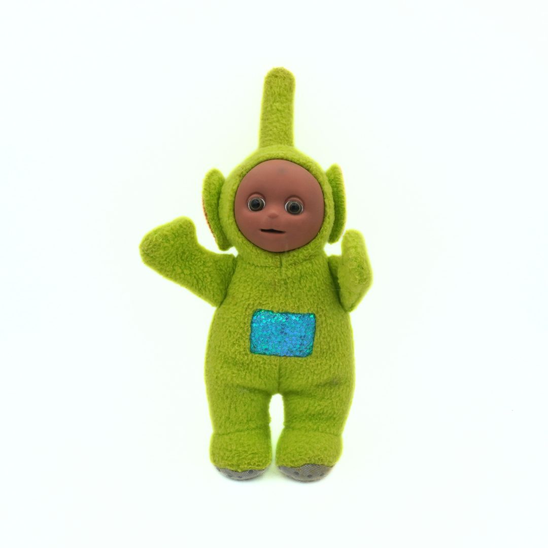Green plush toy with a blue pocket on a white background