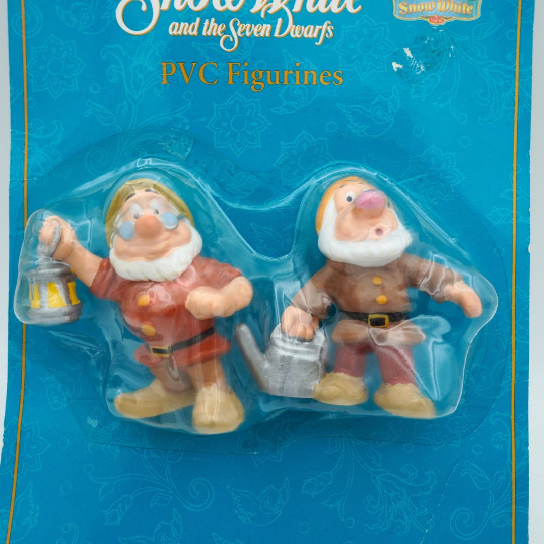 Two PVC figurines of dwarves from Snow White and the Seven Dwarfs in packaging on a blue background.