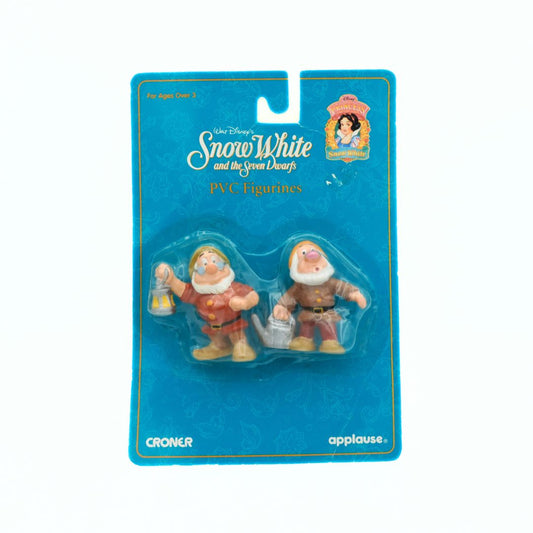Two PVC figurines of dwarfs from Snow White in packaging with Disney branding.