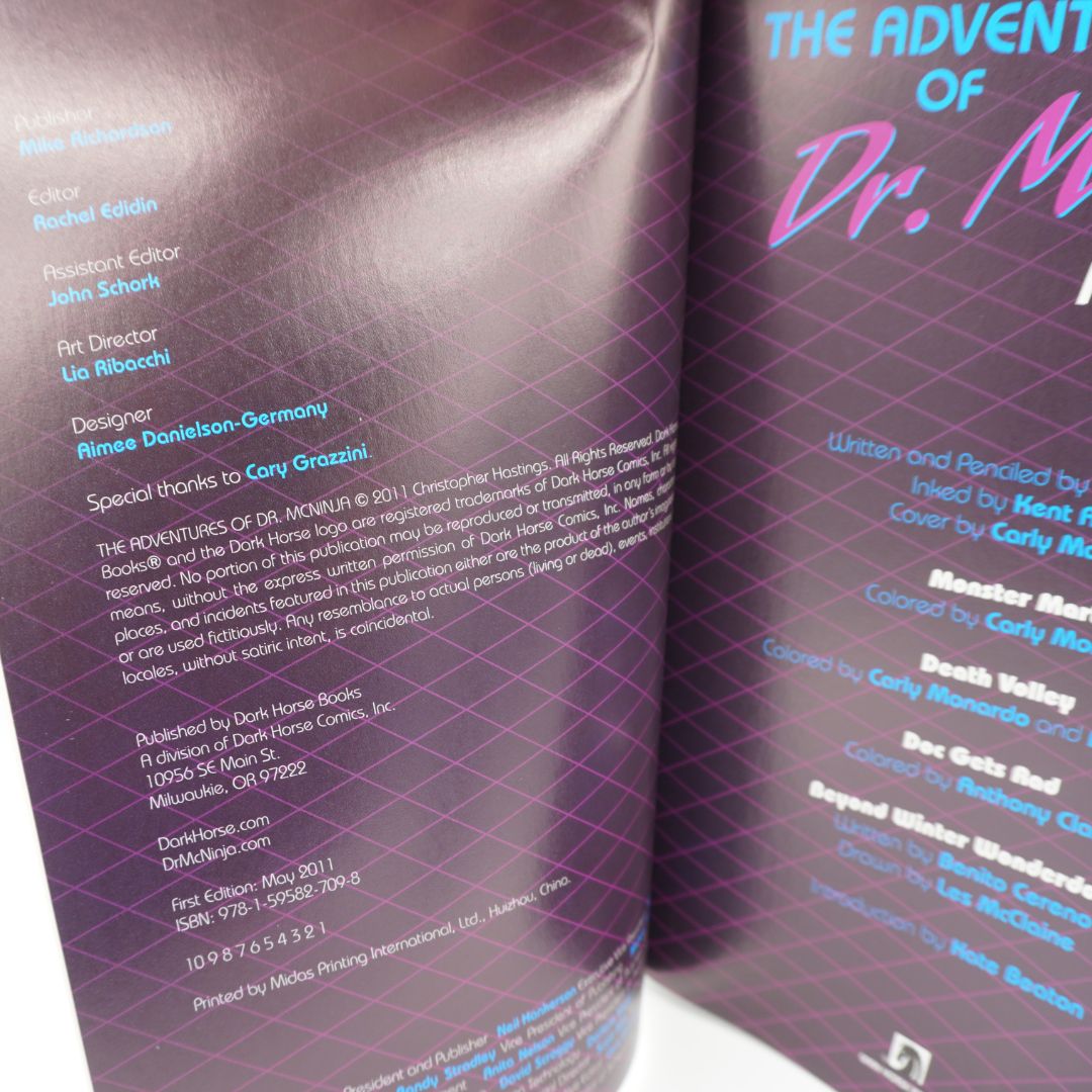 An open book or booklet showing printed cover/interior pages with purple and pink graphics, large text reading 'The Adventures of Dr. McNinja'