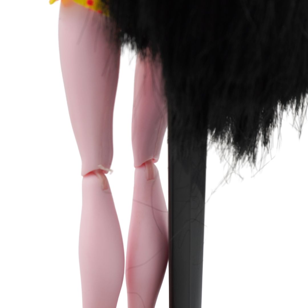 Close up photo of a 2010 Monster High Draculaura from the Gloom Beach range wearing a black shirt and yellow skirt, photographed on a black stand on a white background