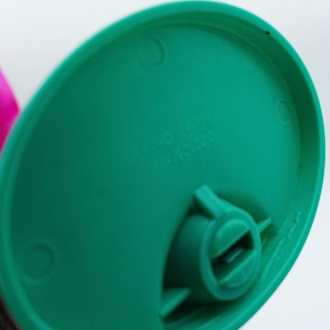 Close-up of a green plastic stand showing molded details and a small pink portion visible at the left edge.
