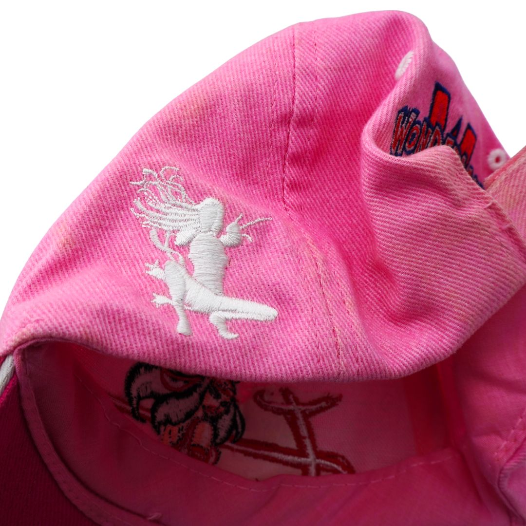 Close-up of a bright pink baseball cap showing white embroidered graphics, including a central figure and partial text on the side.